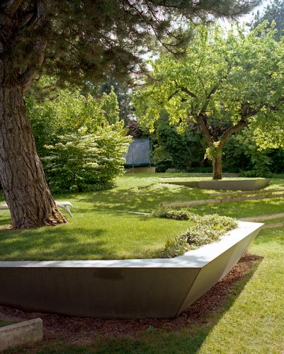 Gartendetail eines modernen Gartens mit altem Baumbestand im Sommer