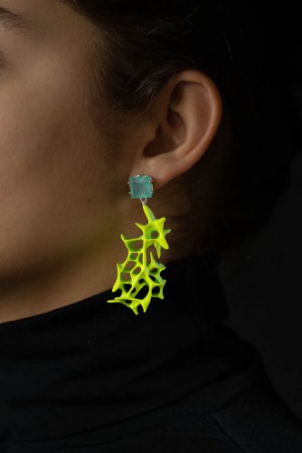 Lilli Veers Jewellery, Portrait mit neonfarbenem Ohrring vor dunklem Hintergrund