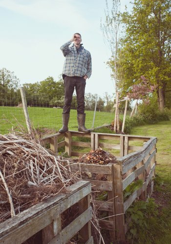 Ausschnitt eines Gartens im Herbst, Mann auf seinem Komposthaufen stehend