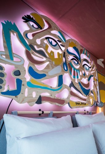 Ausschnitt eines Artrooms im Hotel Villa Viva, beleuchtete Wand Dekoration aus Holz über dem Bett