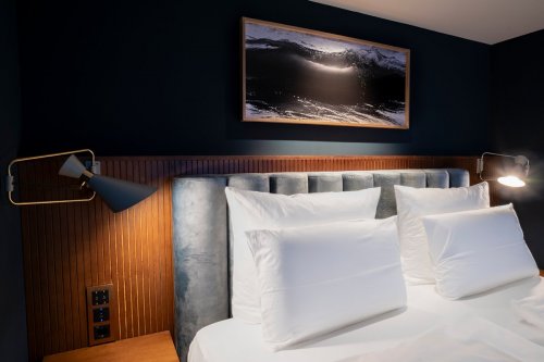 Ausschnitt eines Artrooms im Hotel Villa Viva, beleuchtete Wand Dekoration aus Holz über dem Bett
